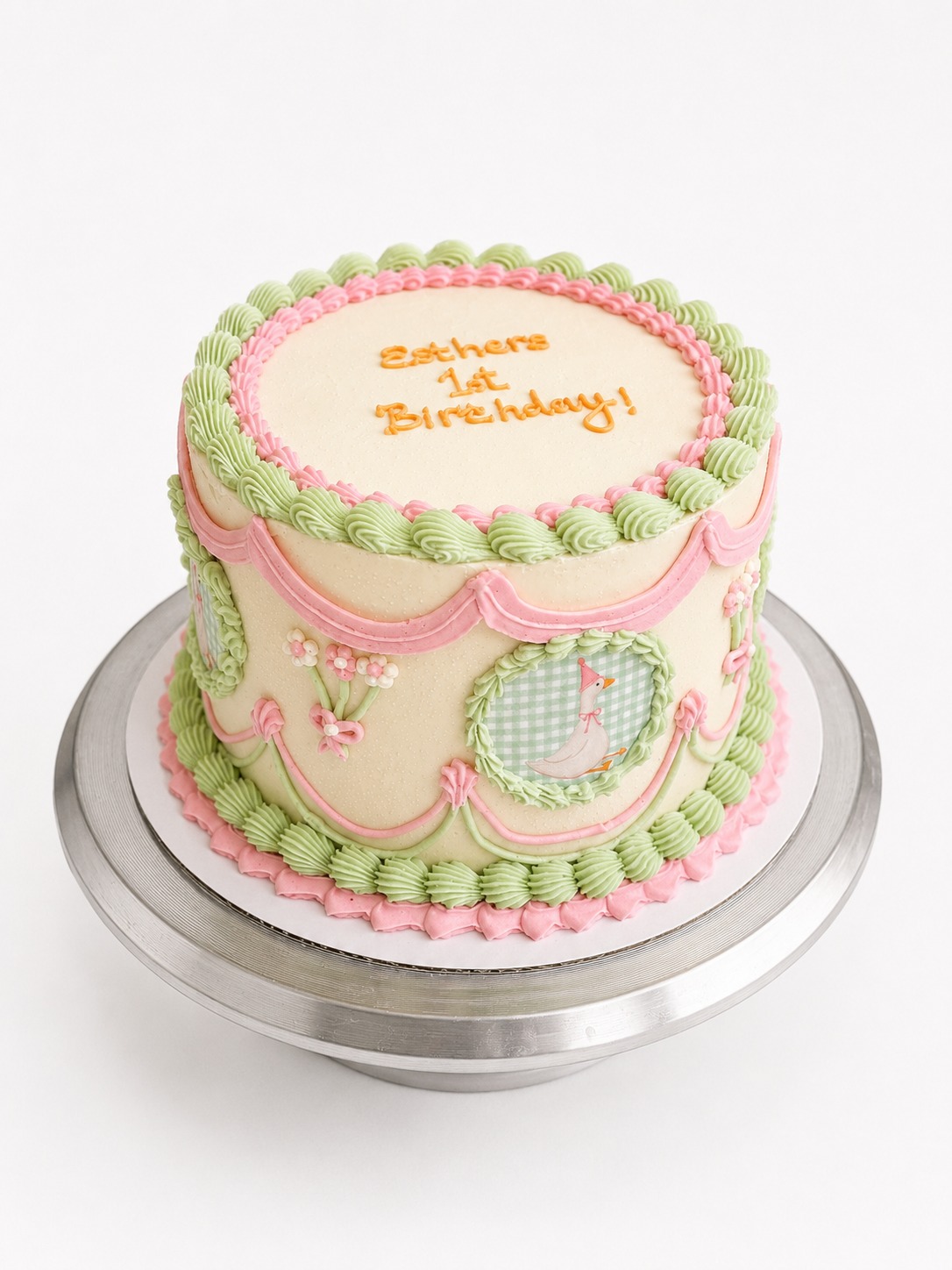 Birthday cake with pastel pink and green piping and a goose illustration